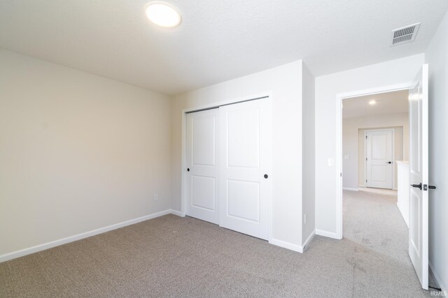 unfurnished bedroom featuring light colored carpet and a closet