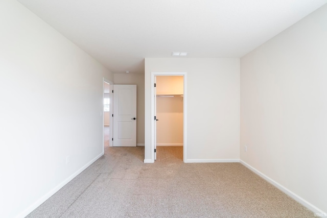 unfurnished bedroom featuring a closet, a spacious closet, and light carpet