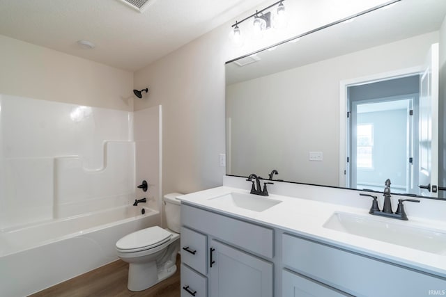 full bathroom with toilet, vanity, hardwood / wood-style flooring, a textured ceiling, and washtub / shower combination