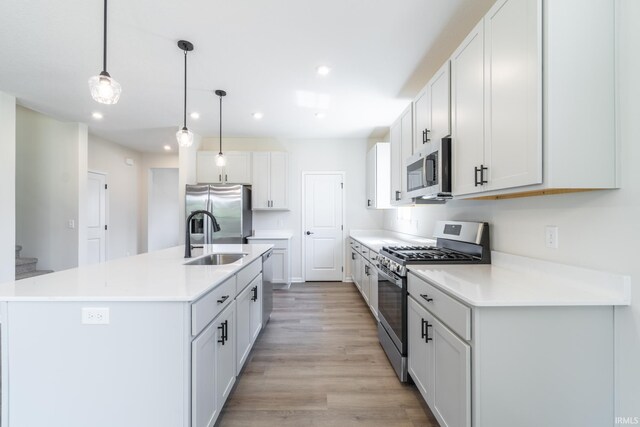 kitchen with hanging light fixtures, sink, appliances with stainless steel finishes, and white cabinetry