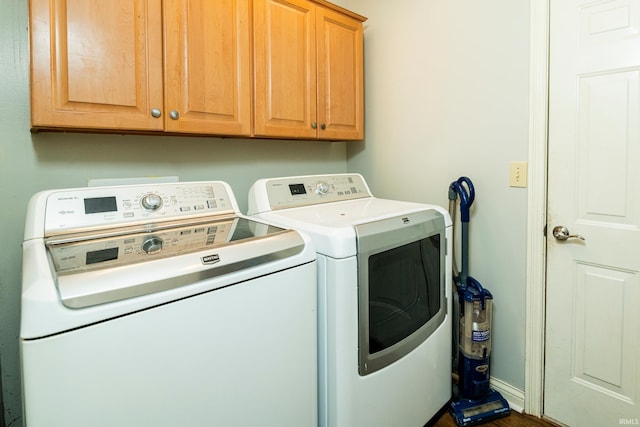 clothes washing area with cabinets and washing machine and dryer