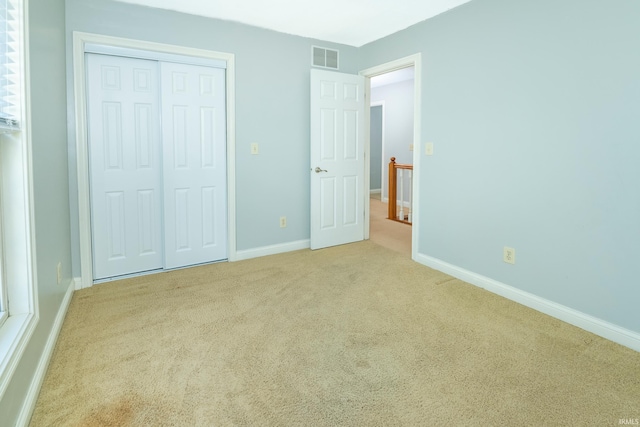 unfurnished bedroom featuring light carpet and a closet