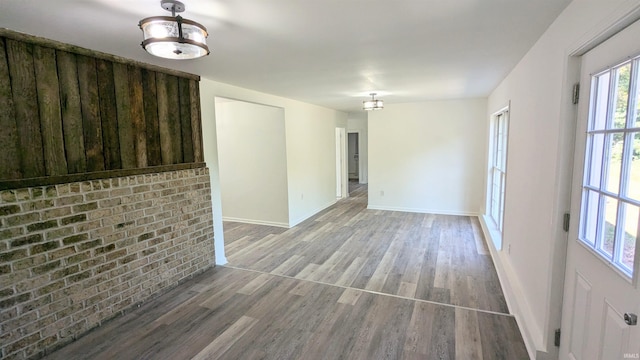 empty room featuring wood-type flooring and brick wall