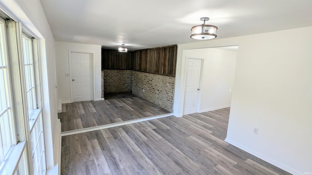 unfurnished room featuring brick wall and light wood-type flooring