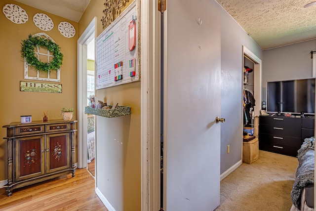 corridor featuring a textured ceiling and light hardwood / wood-style flooring