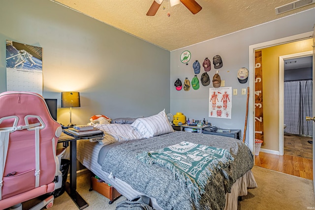 bedroom with a textured ceiling, light hardwood / wood-style flooring, ceiling fan, and vaulted ceiling