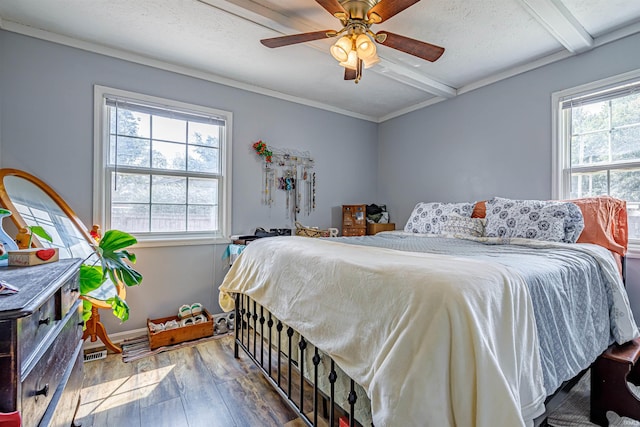 bedroom with multiple windows, beamed ceiling, hardwood / wood-style flooring, and ceiling fan