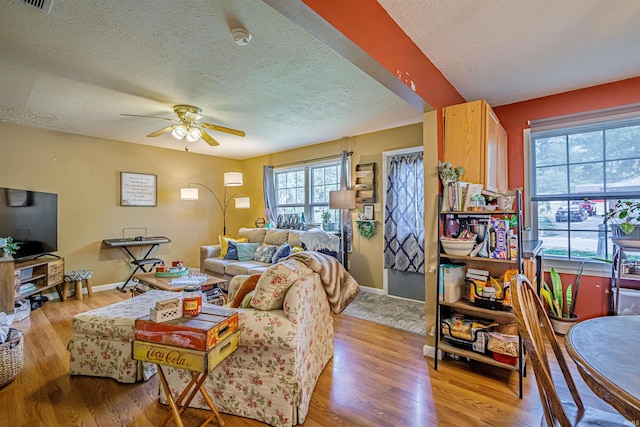 living room featuring a wealth of natural light, ceiling fan, a textured ceiling, and light hardwood / wood-style floors