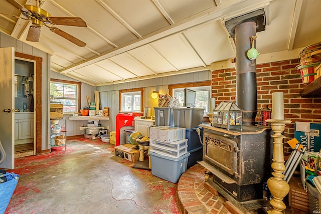 interior space featuring lofted ceiling, concrete flooring, ceiling fan, and a wood stove