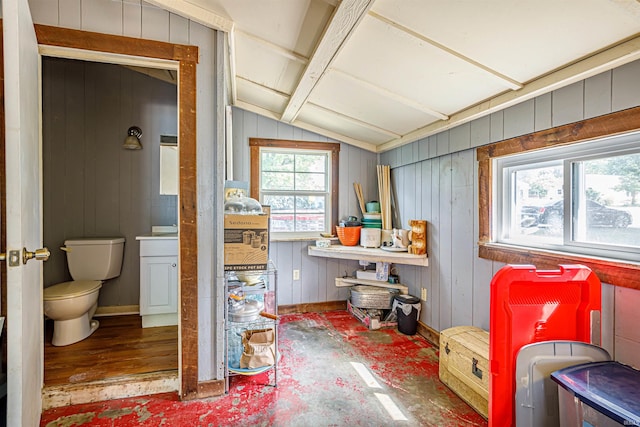 bathroom with vaulted ceiling, toilet, wood-type flooring, and wood walls