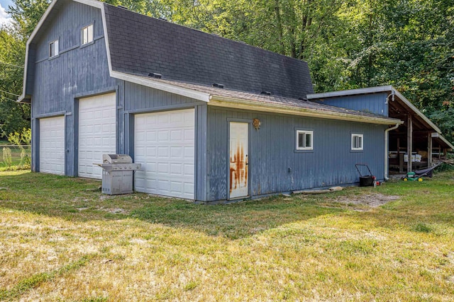 back of property with a garage, a yard, and an outbuilding