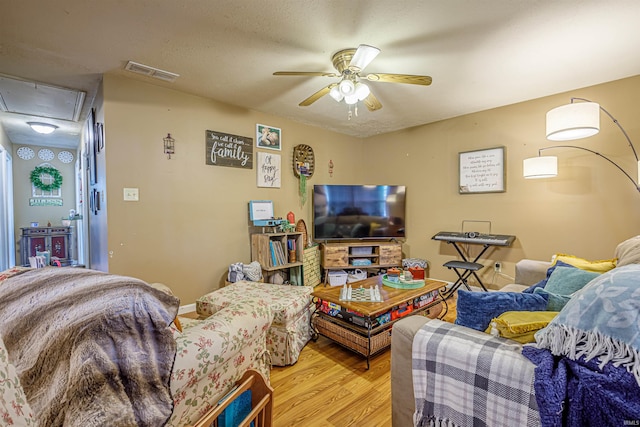 living room with a textured ceiling, ceiling fan, and hardwood / wood-style floors