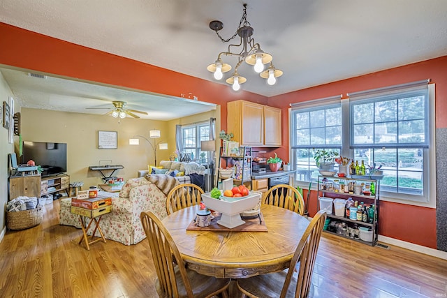 dining room featuring ceiling fan with notable chandelier and light hardwood / wood-style floors