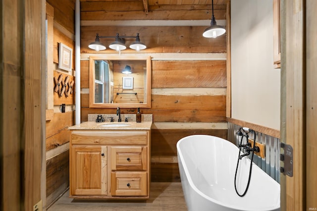 bathroom featuring vanity, wood walls, and a bath