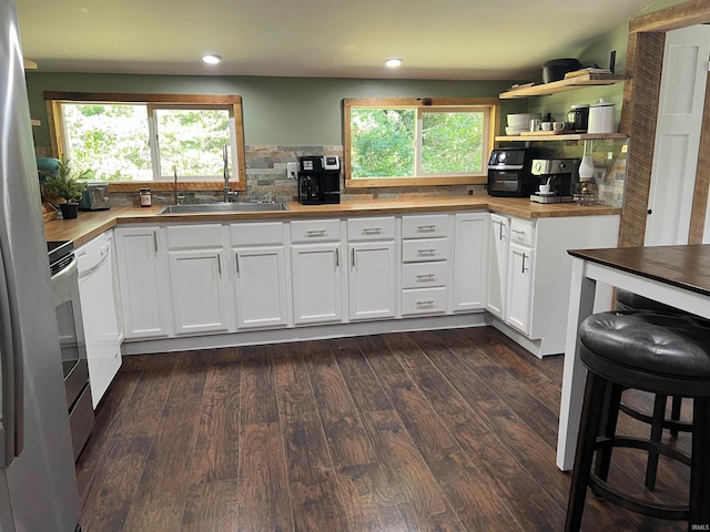 kitchen with decorative backsplash, dark wood-type flooring, white cabinets, butcher block counters, and sink