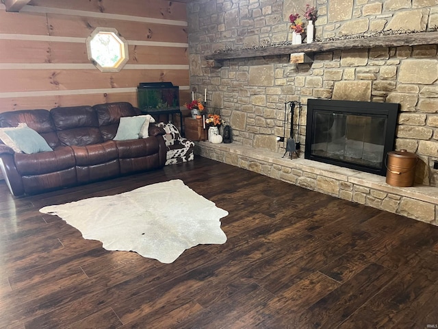 living room with beam ceiling, a fireplace, wood walls, and dark wood-type flooring