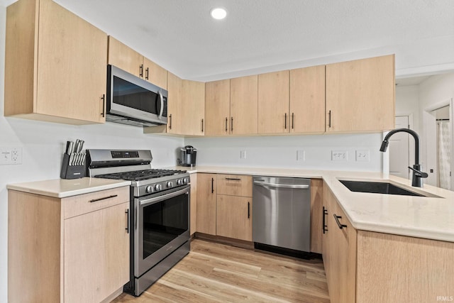 kitchen featuring sink, light brown cabinets, appliances with stainless steel finishes, and light hardwood / wood-style floors