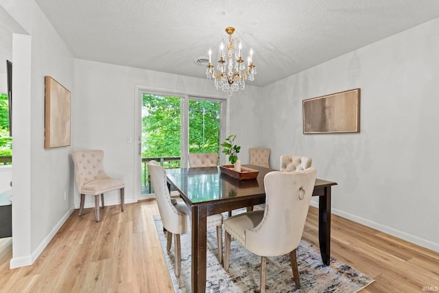 dining area featuring a textured ceiling, light hardwood / wood-style flooring, and an inviting chandelier