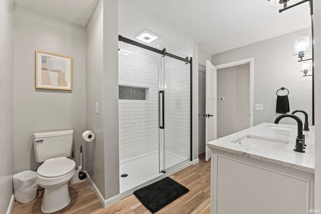 bathroom featuring a textured ceiling, vanity, a shower with shower door, hardwood / wood-style floors, and toilet