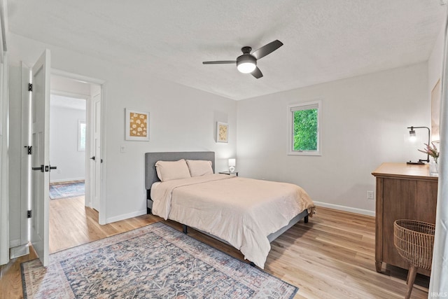 bedroom featuring light wood-type flooring, a textured ceiling, and ceiling fan