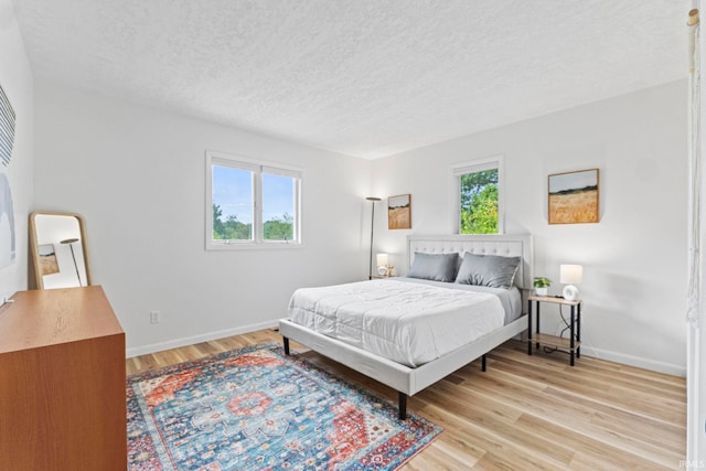 bedroom with light hardwood / wood-style floors and a textured ceiling