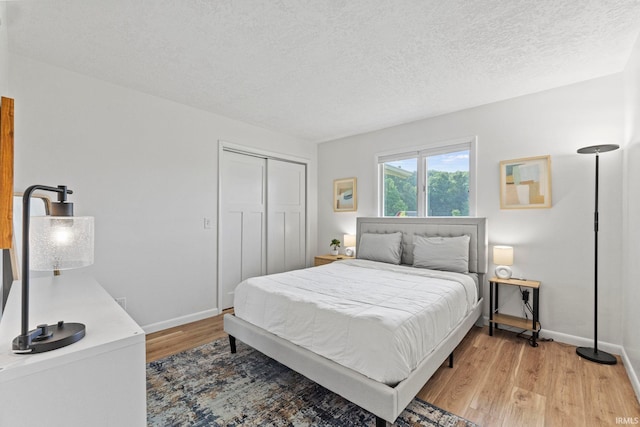 bedroom with light wood-type flooring, a closet, and a textured ceiling