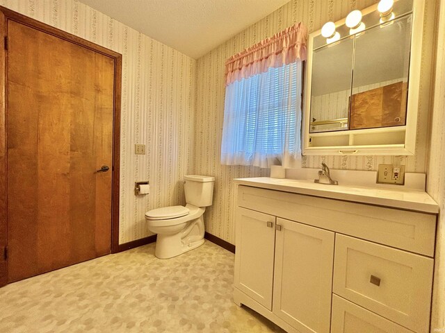 bathroom with vanity, toilet, and a textured ceiling