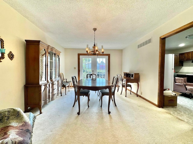 dining room featuring a textured ceiling, light carpet, and french doors