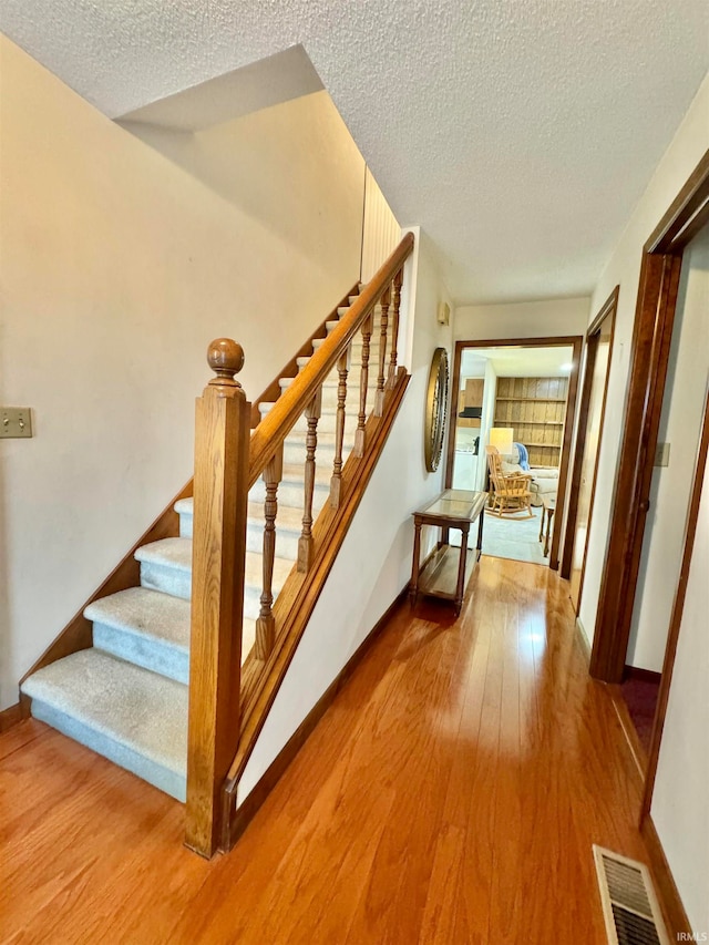 staircase featuring hardwood / wood-style flooring and a textured ceiling