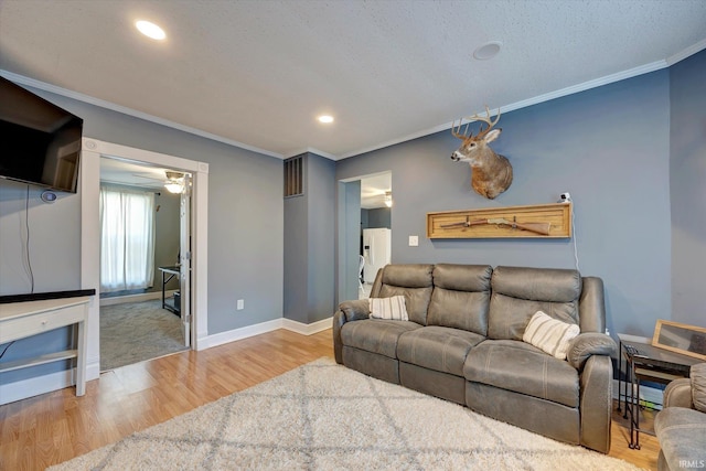 living room featuring ornamental molding, a textured ceiling, hardwood / wood-style flooring, and ceiling fan