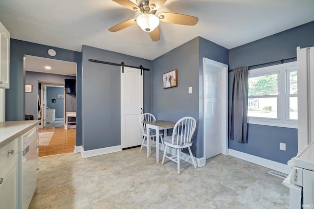 dining area with a barn door, ceiling fan, and light hardwood / wood-style flooring