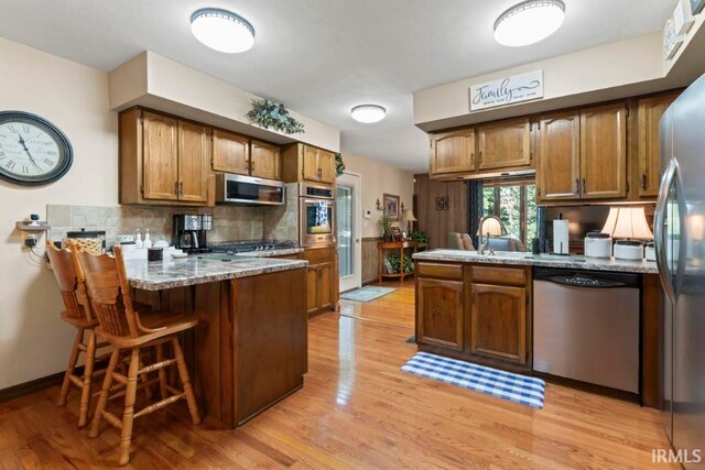 kitchen featuring light wood-type flooring, appliances with stainless steel finishes, and kitchen peninsula