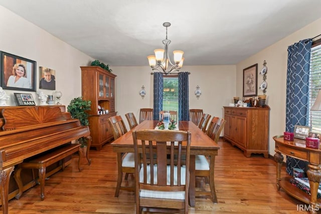 dining space featuring light wood-type flooring and an inviting chandelier