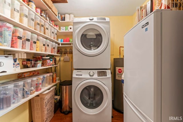 clothes washing area with stacked washing maching and dryer, hardwood / wood-style floors, and water heater