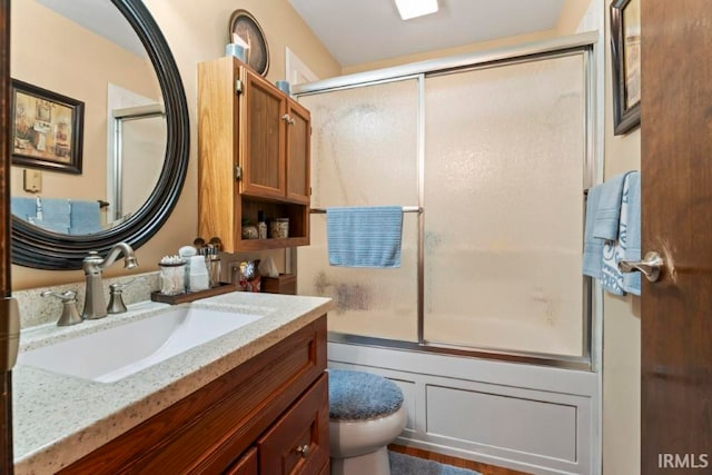 full bathroom with vanity, enclosed tub / shower combo, and toilet