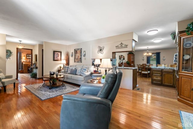 living room with light wood-type flooring and an inviting chandelier