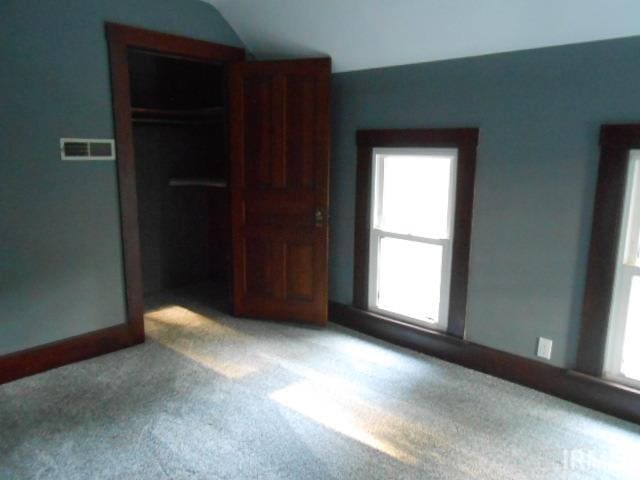 unfurnished bedroom featuring a closet, vaulted ceiling, and light carpet