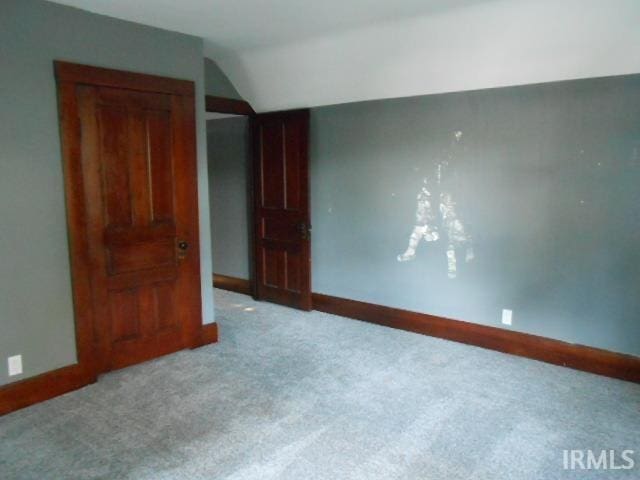 unfurnished bedroom featuring lofted ceiling and carpet floors