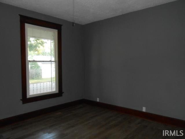 unfurnished room featuring a textured ceiling and dark hardwood / wood-style floors