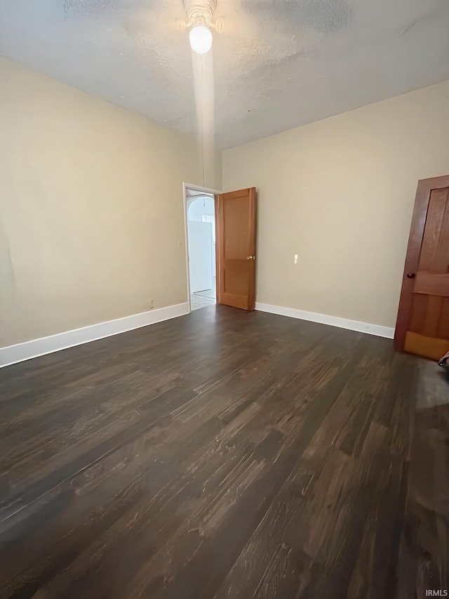 empty room with a textured ceiling and dark hardwood / wood-style floors