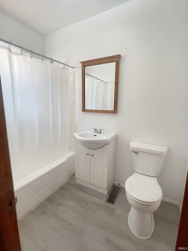 full bathroom with hardwood / wood-style floors, toilet, shower / tub combo with curtain, and vanity