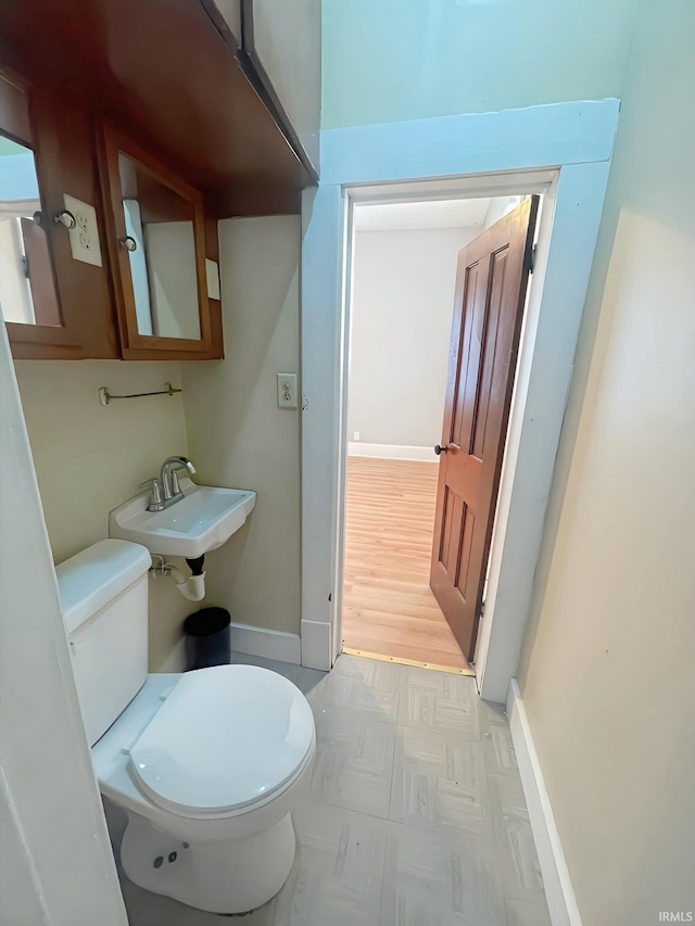 bathroom featuring wood-type flooring, toilet, and sink