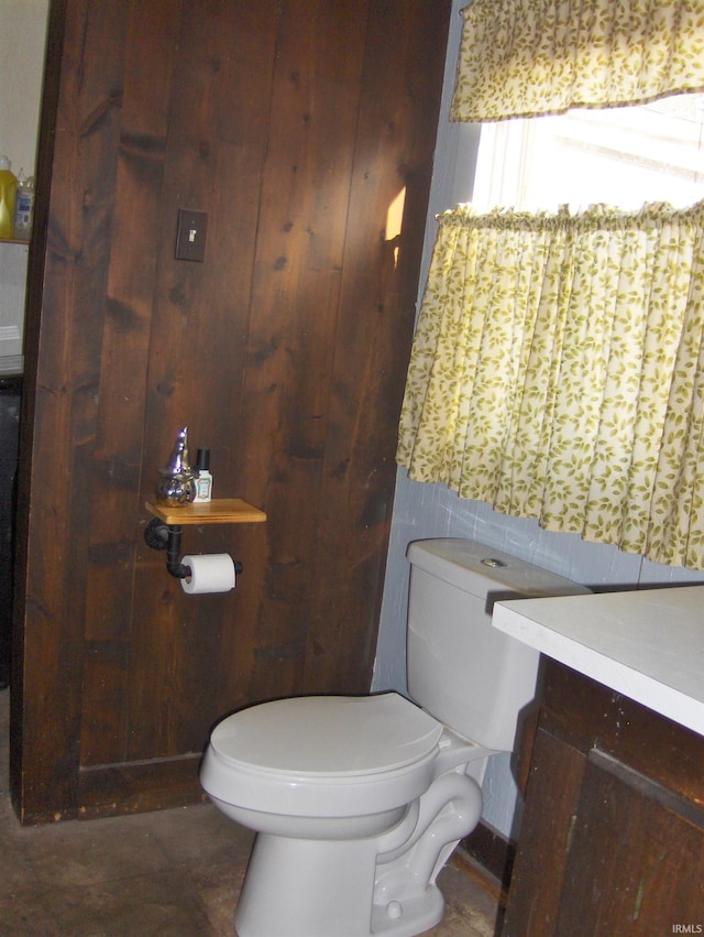 bathroom featuring vanity, toilet, and wood walls