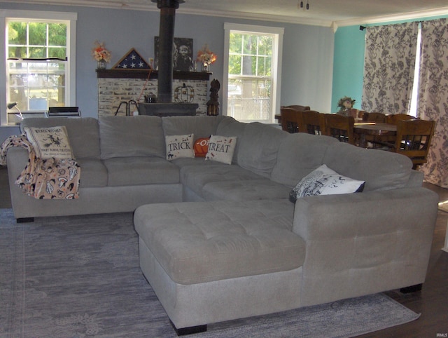 living room featuring wood-type flooring, a wood stove, and crown molding