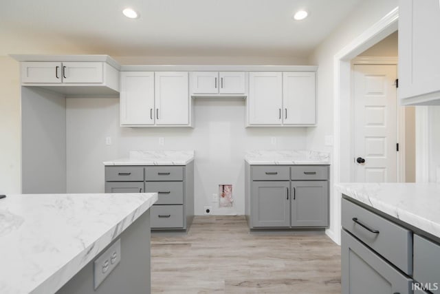 kitchen featuring light stone counters, recessed lighting, light wood finished floors, and gray cabinetry