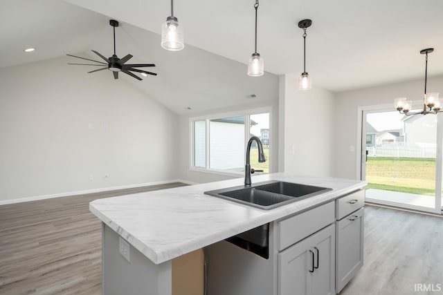 kitchen featuring a center island with sink, dishwasher, open floor plan, decorative light fixtures, and a sink