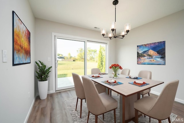 dining space with baseboards, visible vents, a chandelier, and wood finished floors