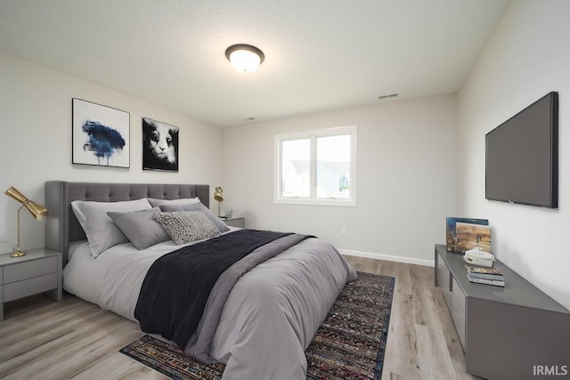 bedroom with light wood-type flooring, visible vents, and baseboards