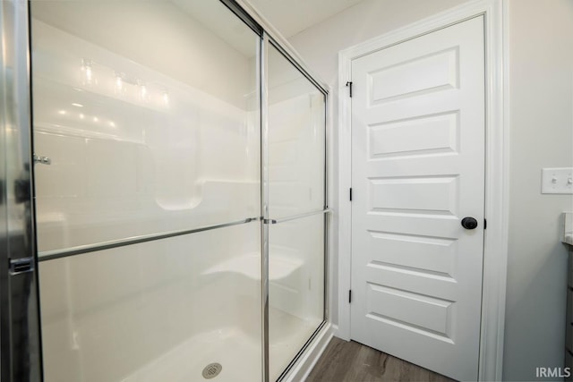 bathroom with a shower stall and wood finished floors