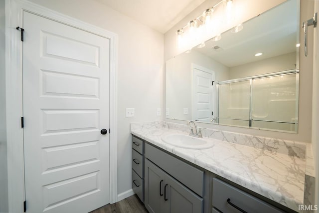 full bathroom with a stall shower, wood finished floors, vanity, and baseboards